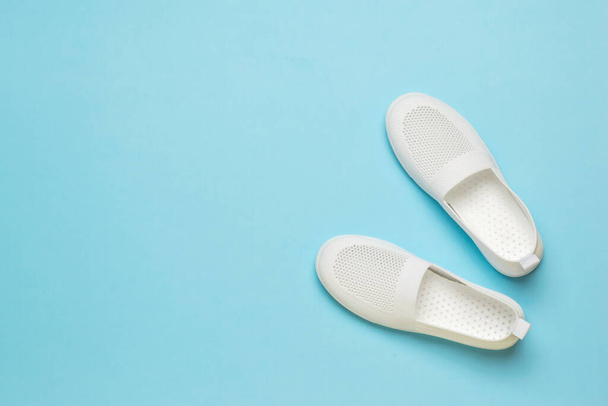 Zapatillas blancas de verano para mujer sobre un fondo azul claro. Zapatos de mujer ligeros. - Foto, imagen
