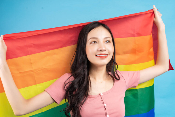 Mujer asiática joven sosteniendo bandera de arco iris para apoyar a la comunidad LGBTQ + - Foto, imagen