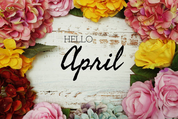 Hello April text and Flowers Colorful Border Frame on wooden background - Photo, Image