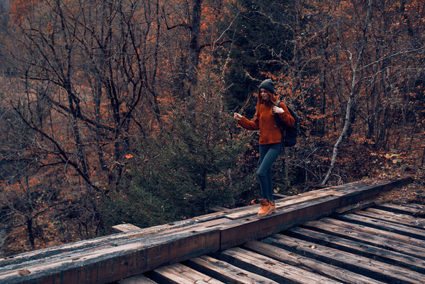 γυναίκα τουρίστρια διασχίζει τη γέφυρα πάνω από το ποτάμι ταξίδια το φθινόπωρο - Φωτογραφία, εικόνα