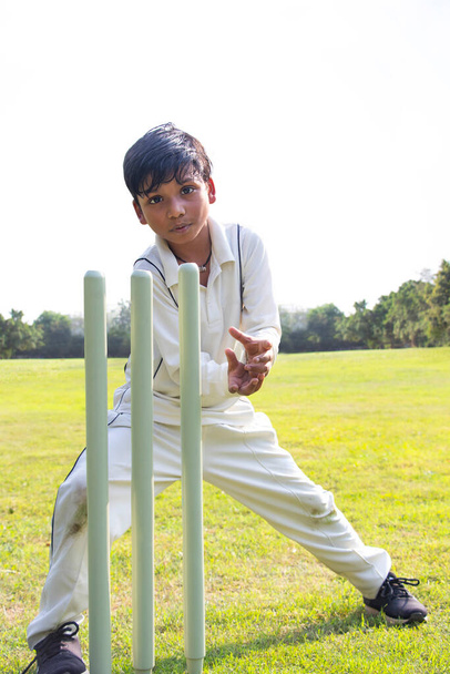 Мальчик полевой на земле во время игры в крикет - Фото, изображение