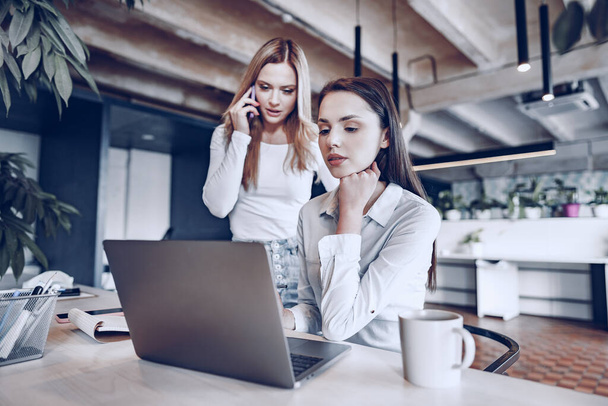 Two young female colleagues discussing business project together in office - Фото, зображення
