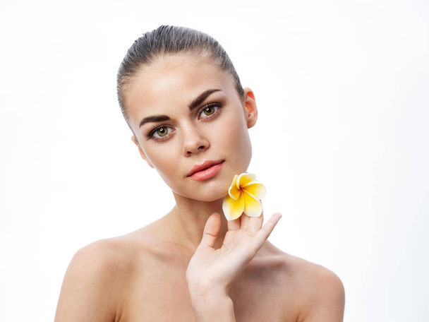 retrato de una mujer desnuda con la piel limpia y una flor amarilla  - Foto, imagen