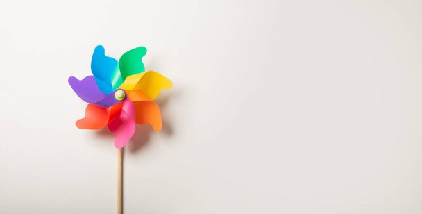 Children's colorful toy wind turbine on white cement wall background - Photo, Image