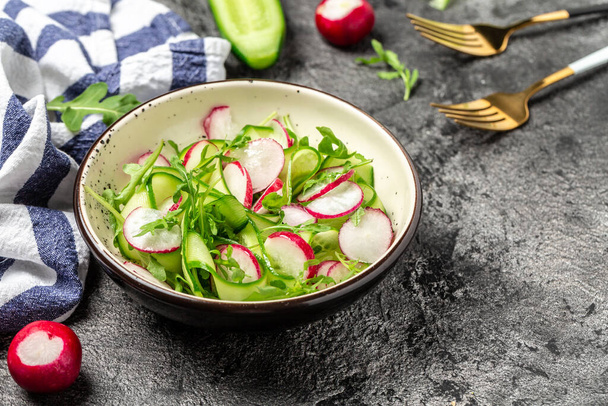 Vegetable salad of fresh cucumbers, radish and arugula. Diet detox food concept. banner, menu recipe place for text, top view. - Фото, изображение