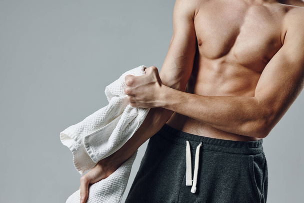 deportista hombre con bombeo muscular cuerpo recortado vista estudio de ejercicios toallas en las manos - Foto, imagen