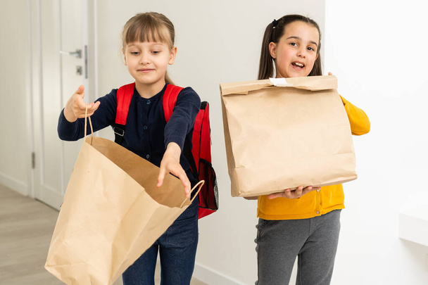 dvě školní dívky s batohem a dodací balíčky ruce v bílém pozadí - Fotografie, Obrázek