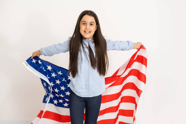 Hermosa niña patriótica con la bandera americana en sus manos extendidas - Foto, Imagen