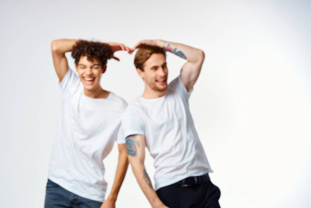 два чоловіки в білих футболках стоять поруч з емоціями дружби
 - Фото, зображення