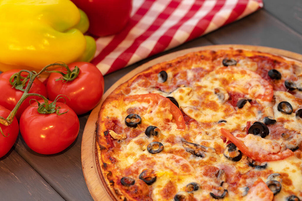 Close up of freshly baked pizza on black wooden table - Foto, imagen