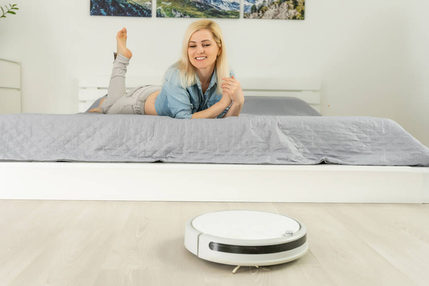 ホームクリーニングコンセプト。現代のロボット掃除機は湿気をきれいにします。新しい技術、迅速な家の掃除自動ロボットアシスタント。洗浄用スマートアプライアンス - 写真・画像