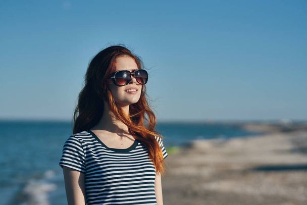 Porträt einer schönen Reisenden mit Brille rote Haare T-Shirt Strand Sommer Landschaft Meer - Foto, Bild