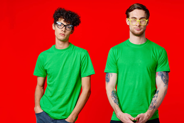 dwóch przyjaciół stoi obok siebie w zielonych koszulkach z okularami - Zdjęcie, obraz