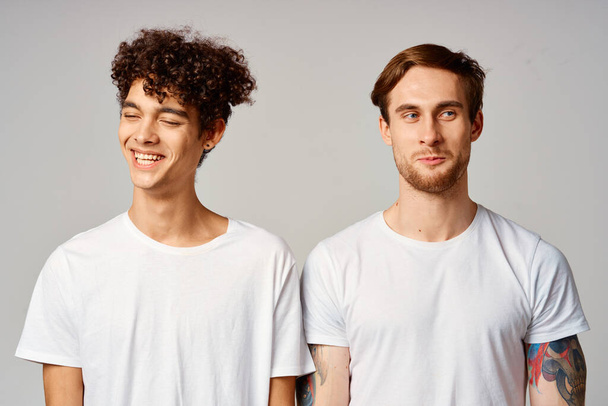 Двое мужчин в белых футболках стоят рядом с эмоциями дружбы - Фото, изображение