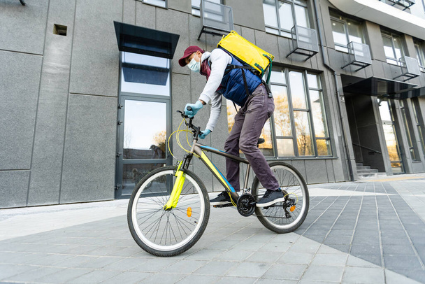 жовтий термальний рюкзак і велосипед в місті. концепція доставки продуктів харчування
. - Фото, зображення
