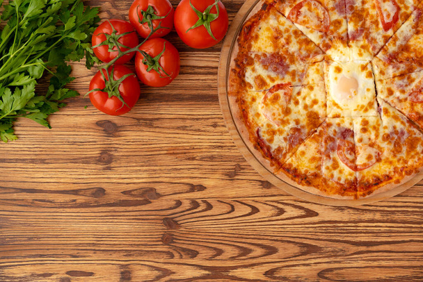 Top view of freshly baked pizza on wooden background - Photo, image