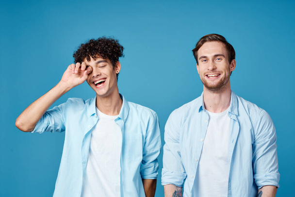 miehet identtisissä paidoissa ja valkoisissa t-paidoissa sinisellä pohjalla juttelemassa kavereiden kanssa rajattu näkymä - Valokuva, kuva