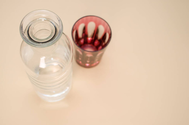 A closeup shot of a red and clear glass bottle isolated on a pink surface with space for text - Photo, image