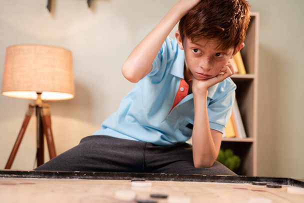 Overthinking Confused Caucasian kid scratching head to decide which coin to hit while playing carrom board - concept of mental illness and development - Φωτογραφία, εικόνα
