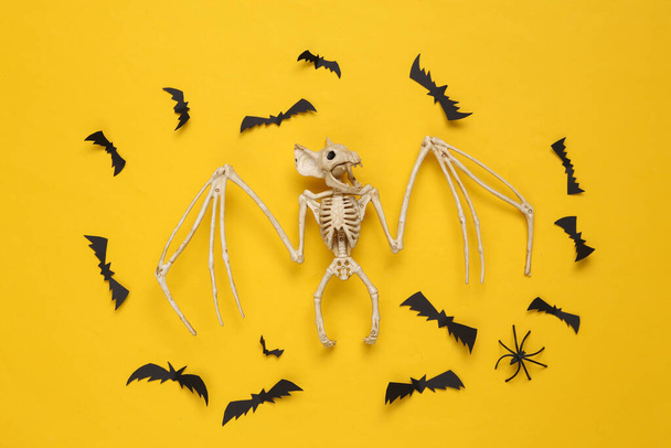 Creative halloween layout. Vampire bat skeleton and flying bats on a yellow background. Flat lay. Top view  - Zdjęcie, obraz