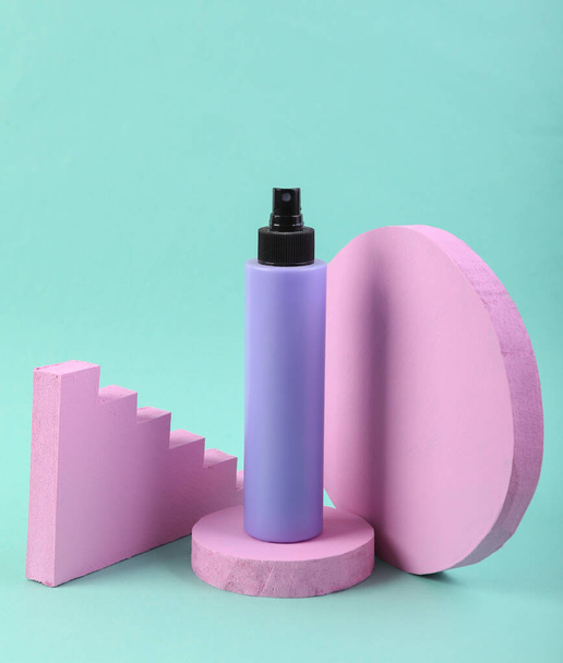 Roze podium met Haarspray fles op blauwe achtergrond. Productpresentatie. Abstracte geometrische samenstelling in minimaal ontwerp. - Foto, afbeelding