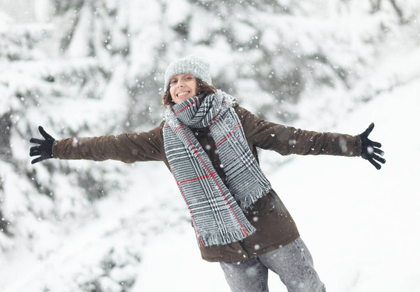 Cheerful woman in warm clothes enjoying the falling snow - Foto, afbeelding