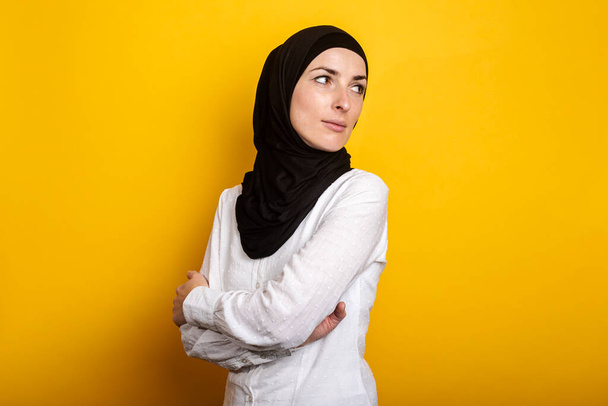 Młoda muzułmanka w hidżabie spogląda w bok i patrzy wstecz na żółte tło. Sztandar. - Zdjęcie, obraz
