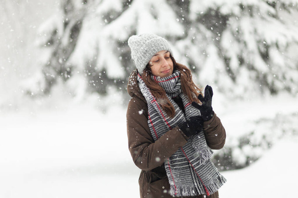 Woman in warm clothes putting on gloves in winter snowy weather - Fotó, kép