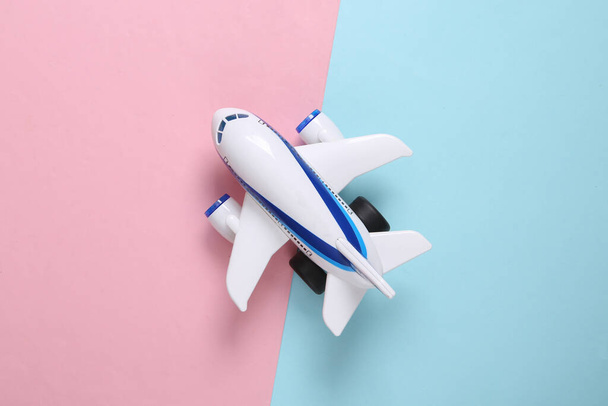 Модель іграшкового пасажирського літака на синьо-рожевому пастельному тлі. Концепція подорожей. Вид зверху
 - Фото, зображення