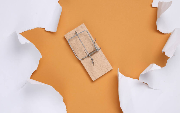 Mousetrap and white torn paper sheets on beige background. Minimalistic background. Top view. Copy space - Photo, Image