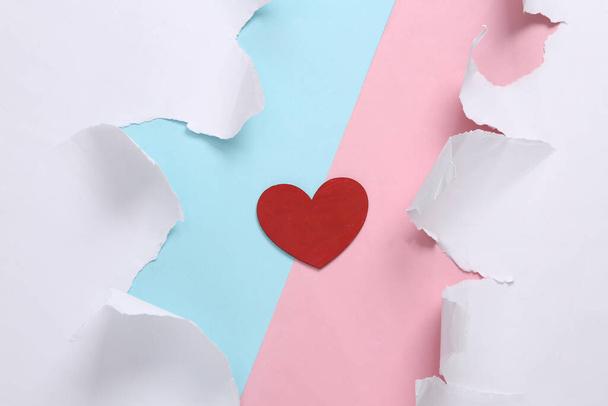 愛の概念。引き裂かれた紙で青ピンクの背景に赤いハート。コンセプトアート。パステルカラーのトレンド。創造的なレイアウト。ミニマリズム。トップ表示 - 写真・画像