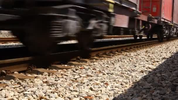 Nízký úhel pohledu na podvozek dlouhého složení, nákladní železniční vlak, který projíždí průmyslovým venkovem. - Záběry, video