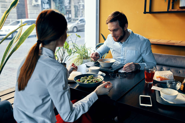 背景にある飲食店のテーブルで夕食をとるシャツの男と女熱い飲み物 - 写真・画像