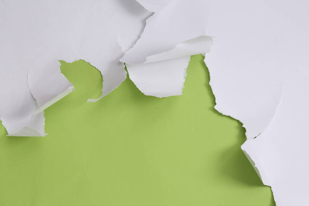 Feuilles de papier déchiré blanc sur fond vert. Contexte minimaliste. Espace de copie - Photo, image