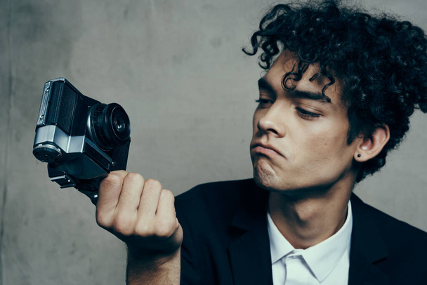 κομψό άνθρωπος με κάμερα στο χέρι φωτογραφικό στούντιο μπούκλες μοντέλο πορτρέτο - Φωτογραφία, εικόνα