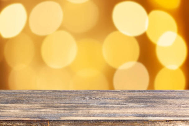 wood table top on blur yellow christmas tree lights background - Foto, afbeelding