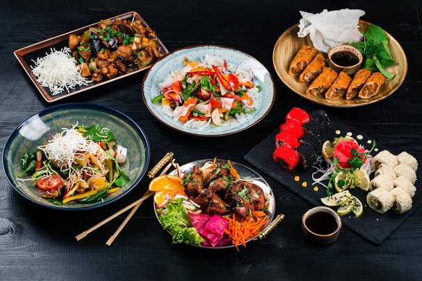 asian food assorted set on the table, Wok, noodles and vegetables salad and chopsticks on dark rustic background. Chinese dishes, Asian style - 写真・画像