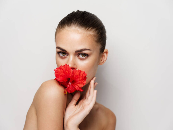 ładna kobieta czerwony kwiat gołe ramiona studio jasne skóra - Zdjęcie, obraz