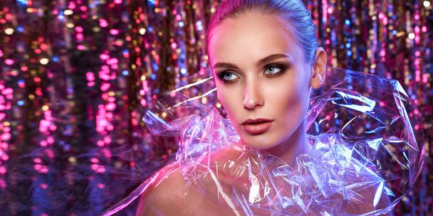 High Fashion model girl in colorful bright neon lights posing in studio through transparent film. Portrait of beautiful woman in UV. Art design colorful make up. On colourful vivid background - Foto, afbeelding
