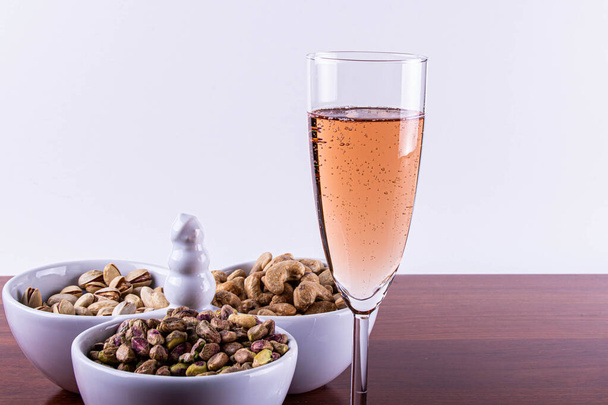 Verre de vin mousseux rose aux noix mélangées. . - Photo, image