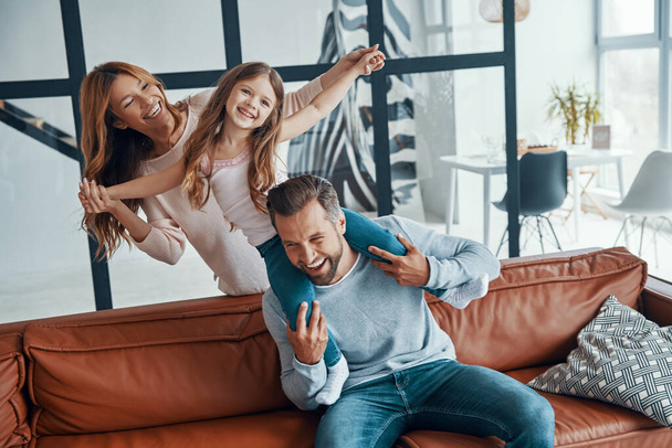 Fröhliche junge Familie beim Zusammensitzen auf dem heimischen Sofa - Foto, Bild