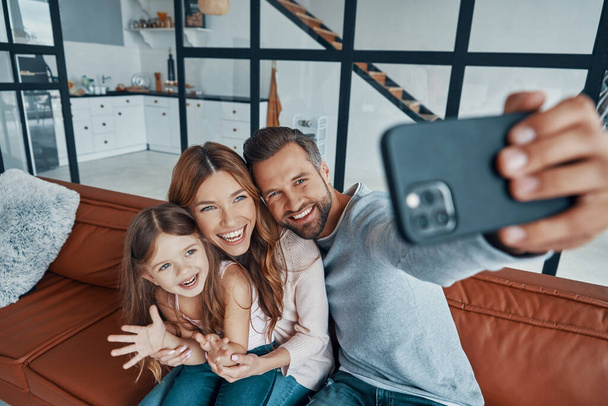Happy young family smiling and using smart phone to take a selfie  - Fotografie, Obrázek