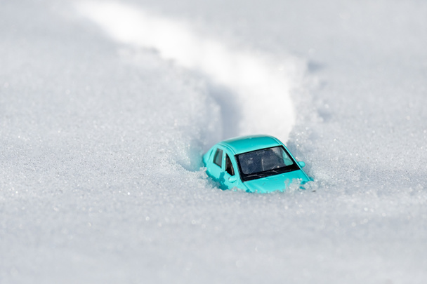 Nur das Dach des Spielzeugautos ragt aus dem Schnee. im Schnee stecken geblieben - Foto, Bild