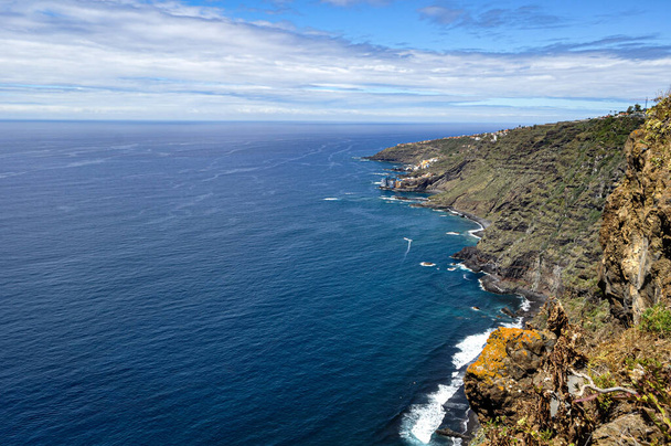 The blue sea contrasts with the greens and browns of the coast with the black sand beaches - Foto, afbeelding