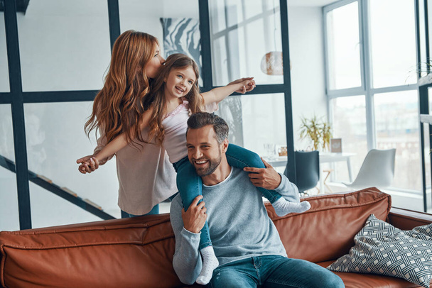 Beautiful young family smiling and embracing while bonding together at home - Φωτογραφία, εικόνα