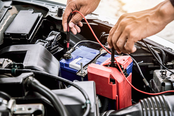 Close up hand of auto mechanic are using measuring equipment tool for checking car battery. Concepts of car fix repair and service maintenance. - Φωτογραφία, εικόνα