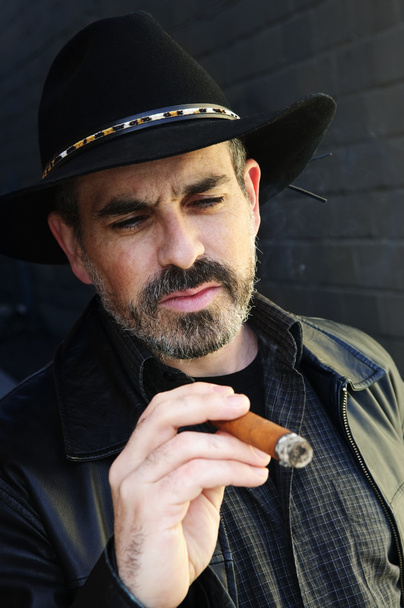 Man with beard in cowboy hat smoking cigar - Foto, Imagen