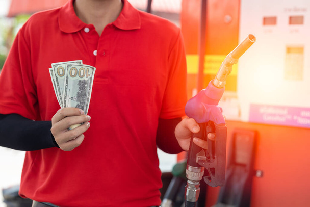 Concepto de ahorro de combustible, personal trabajador mano celebración de dinero en efectivo en la gasolinera - Foto, imagen