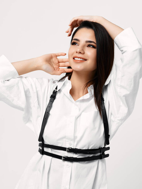 mulher sexy em camisa branca com suspensórios pretos segura as mãos atrás de sua cabeça - Foto, Imagem