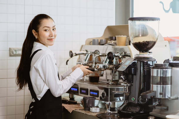 Kahveci kadın kahve makinesi ile kahve yapıyor. Kahve makinesinde mutlu bir gülüş kamerası var.. - Fotoğraf, Görsel